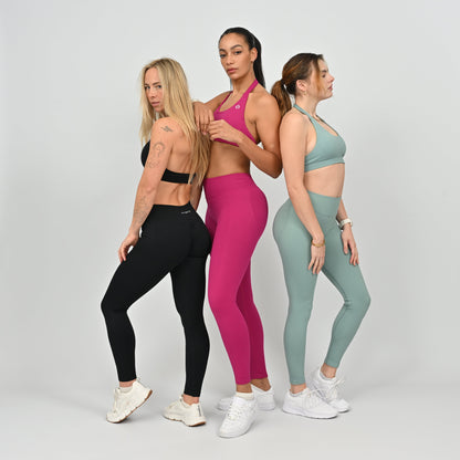 Three women wearing colorful athletic wear from Hybryd. 
