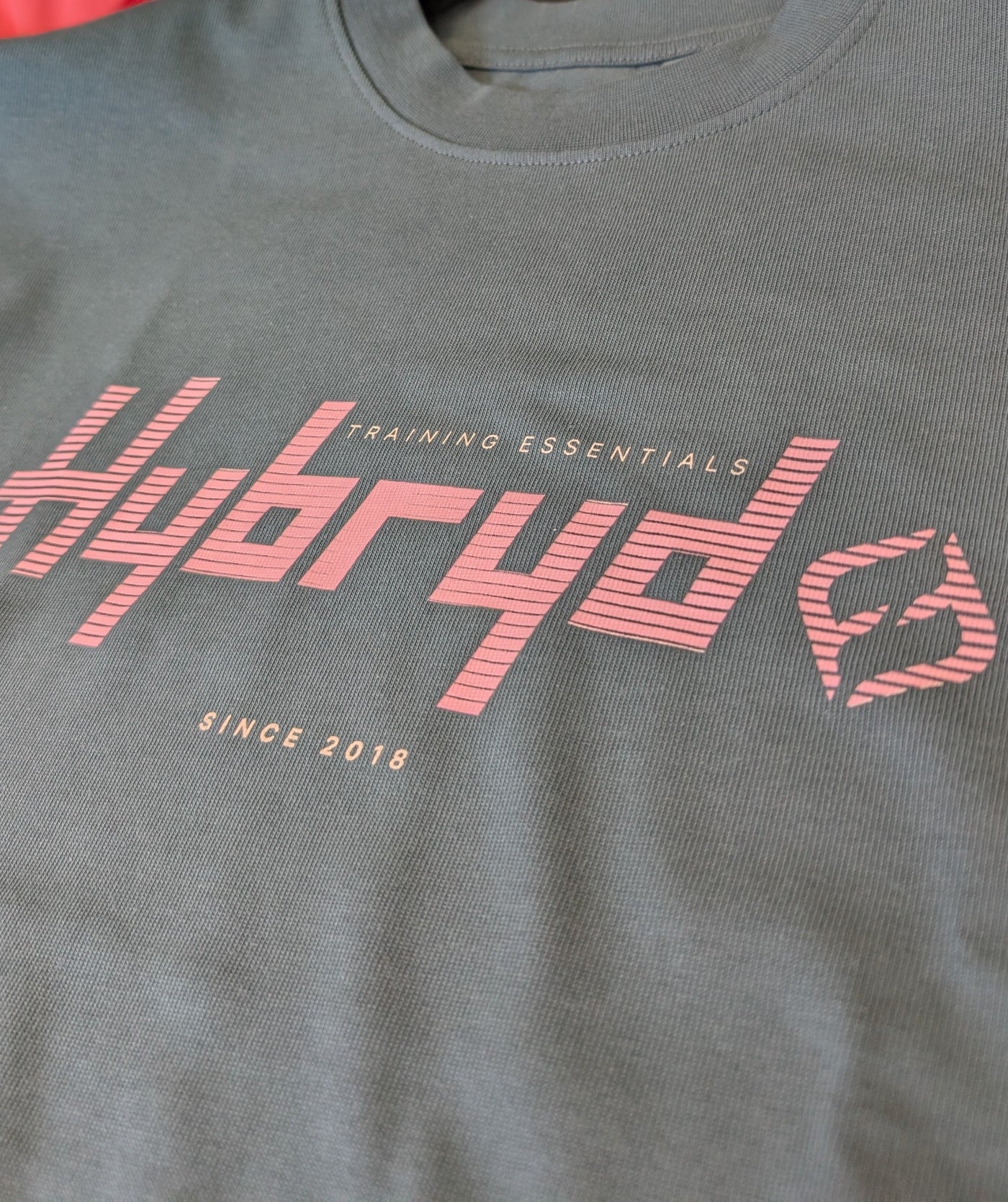 close up of logo on a teal Hybryd Tee