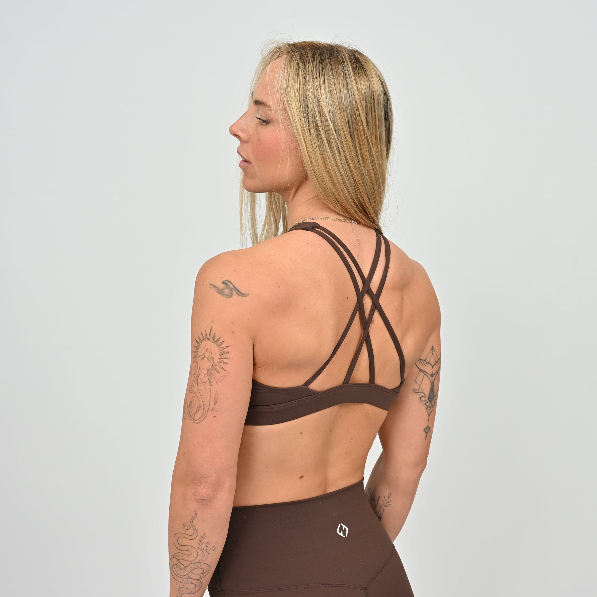 Woman wearing a brown sports bra and leggings from Hybryd activewear.