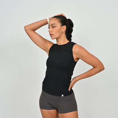 Woman wearing a Hybryd black sleeveless vest top. Worn with grey gym shorts