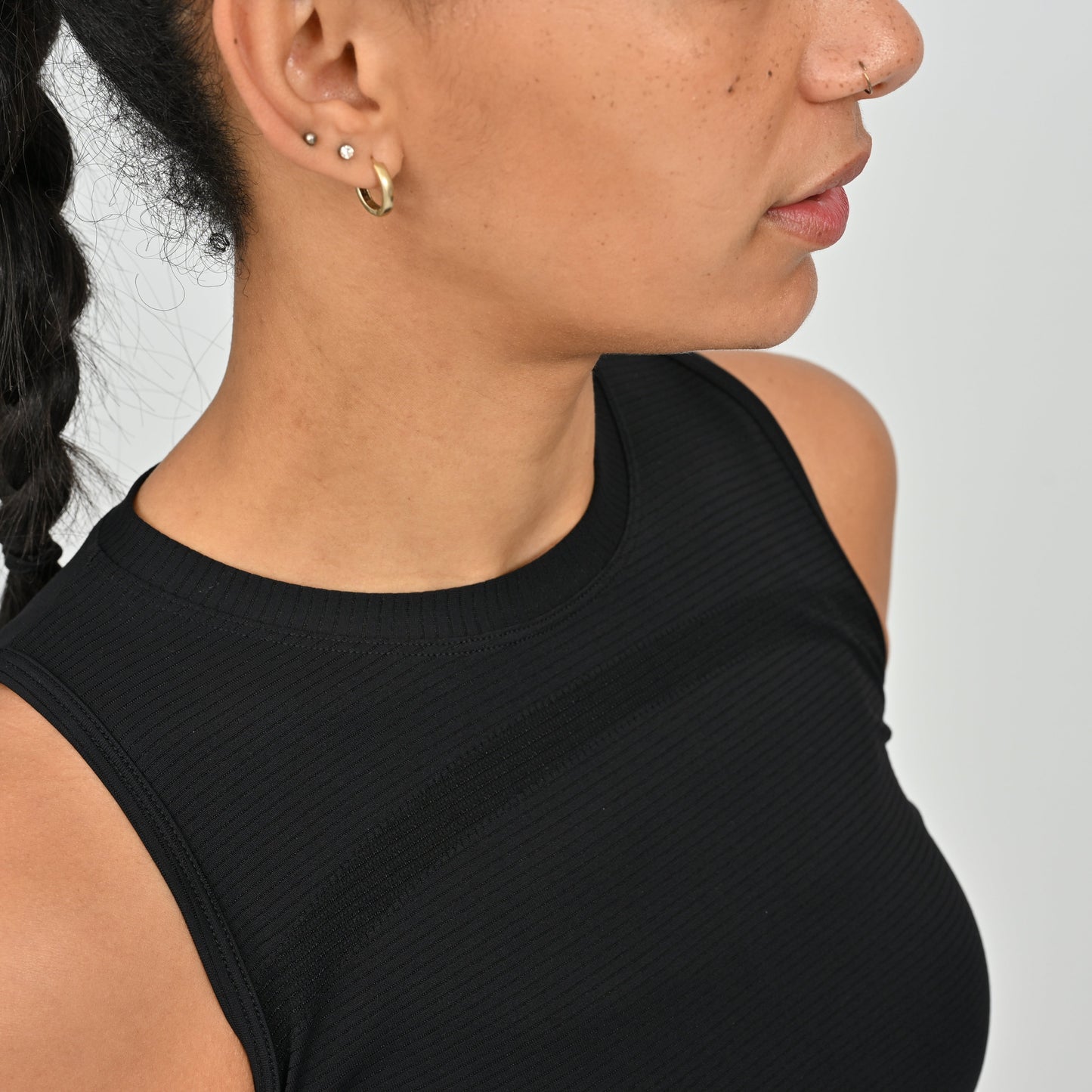 Close-up of a person wearing a black sleeveless activewear vest top from gymwear brand Hybryd