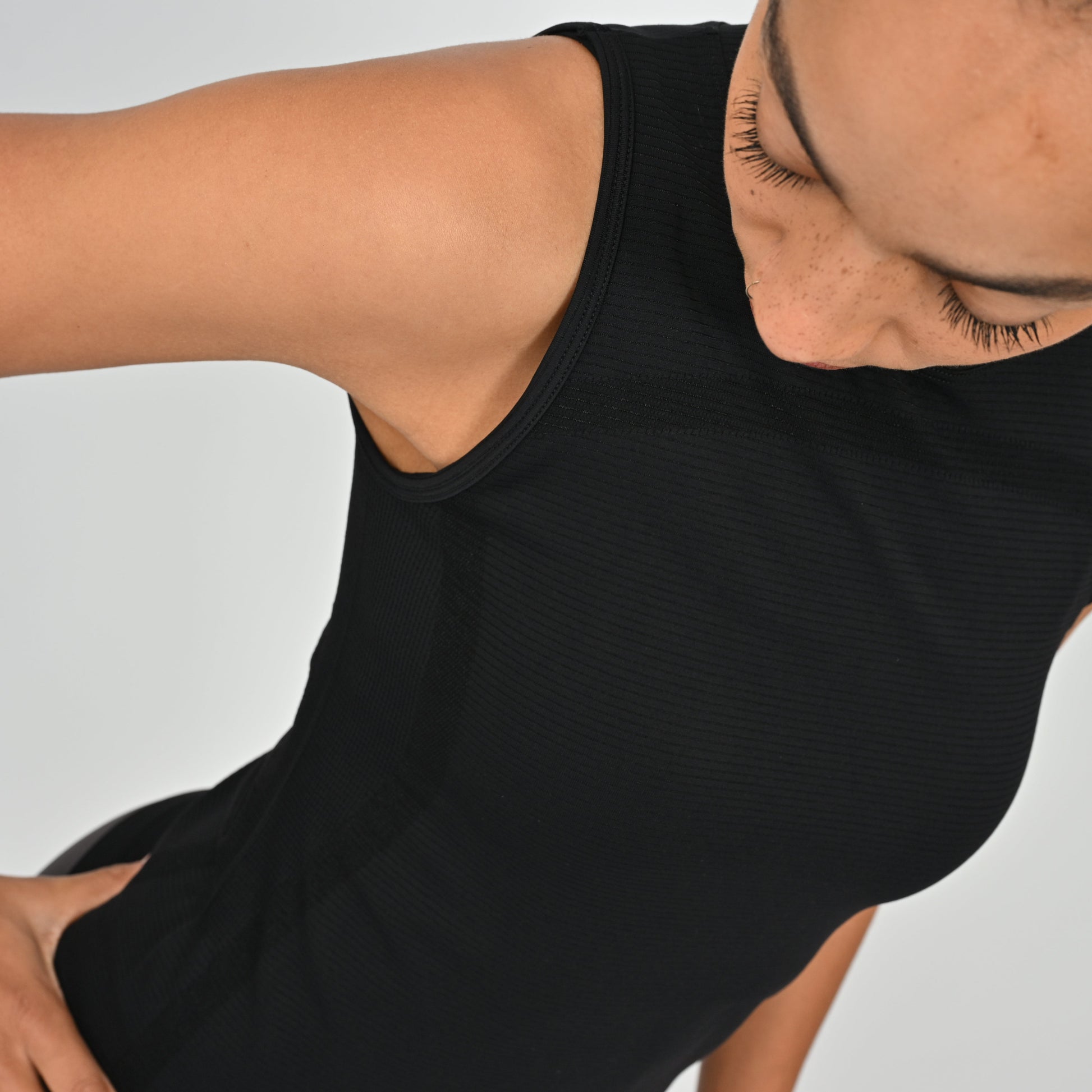Person wearing a black Hybryd sleeveless top on a light gray background