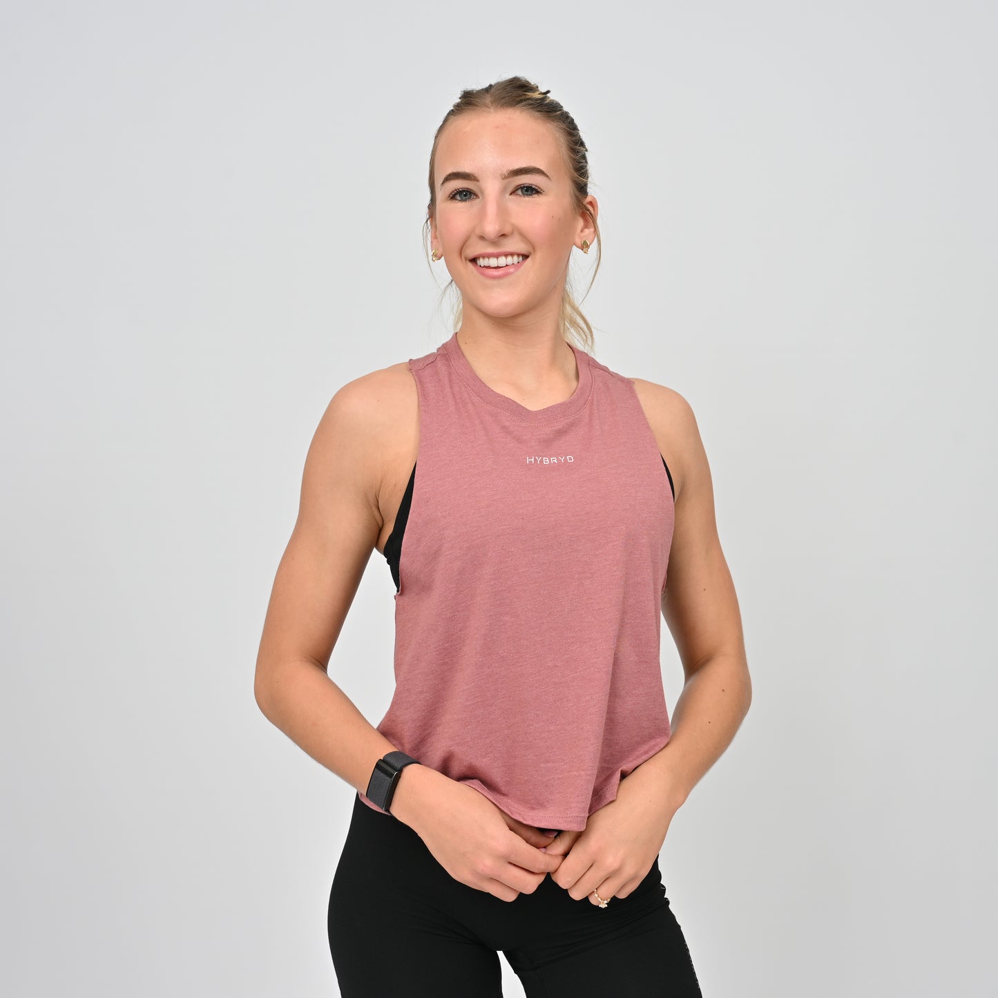 Woman wearing a pink hybryd sleeveless top with a logo on a light gray background