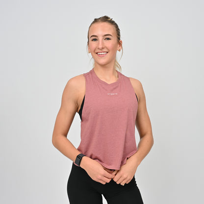 Woman wearing a pink hybryd sleeveless top with a logo on a light gray background