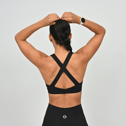 Person wearing a black Hybryd sports bra with criss-cross straps.