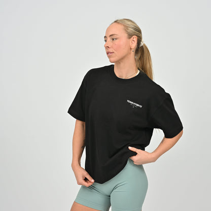 Woman wearing a black t-shirt with 'TEAM HYBRYD' logo on a plain background