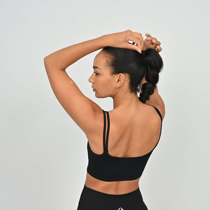 Woman wearing a Hybryd black gymwear bra and leggings against a light gray background