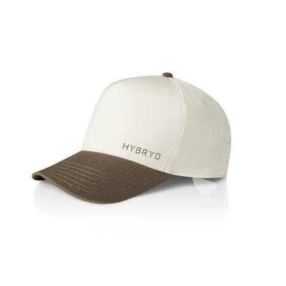 A structured baseball cap with an off-white crown and a brown curved brim, featuring the brand name 'HYBRYD' on the front. The cap is photographed on a clean white background with a soft reflection underneath.