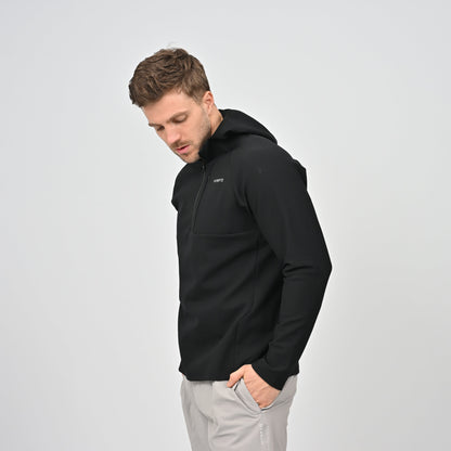 Man wearing a black Hybryd jacket with a logo on a light gray background