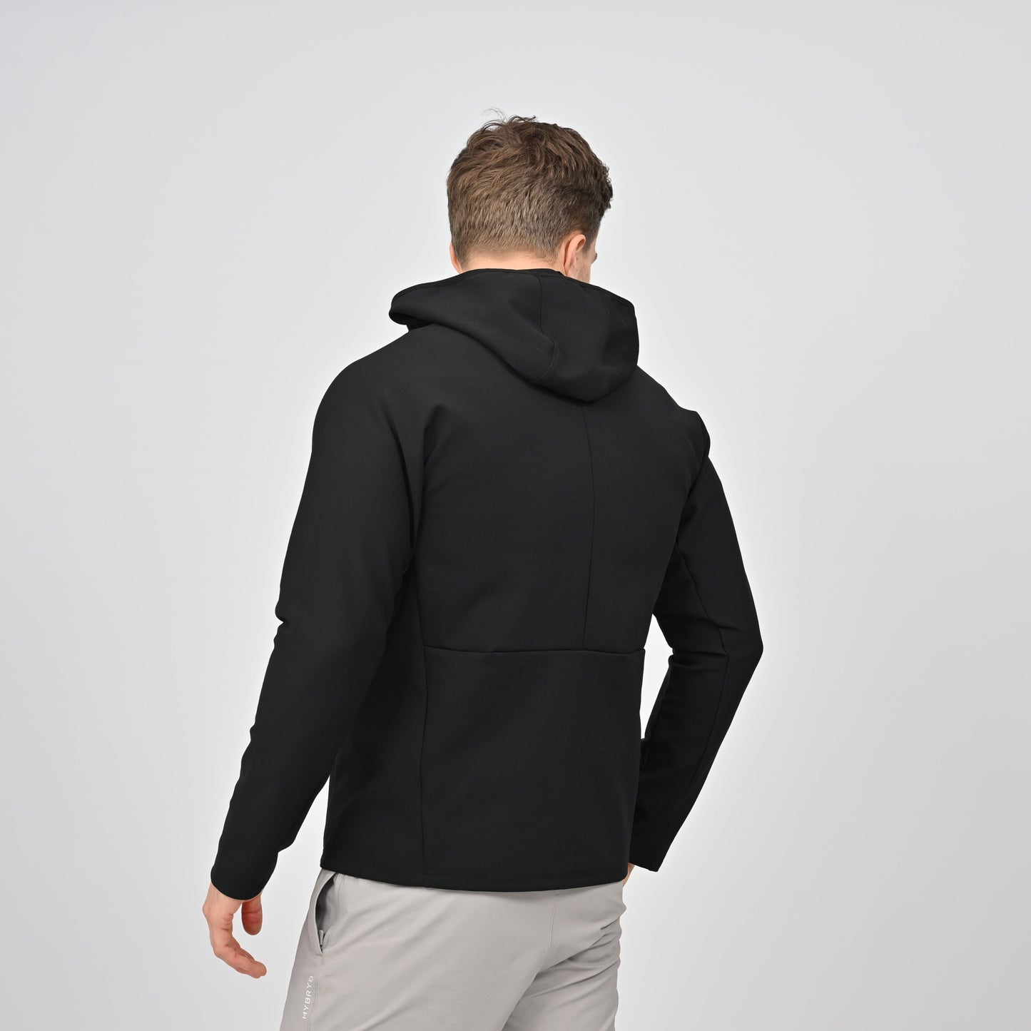 Man wearing a black Hybryd hoodie on a light gray background