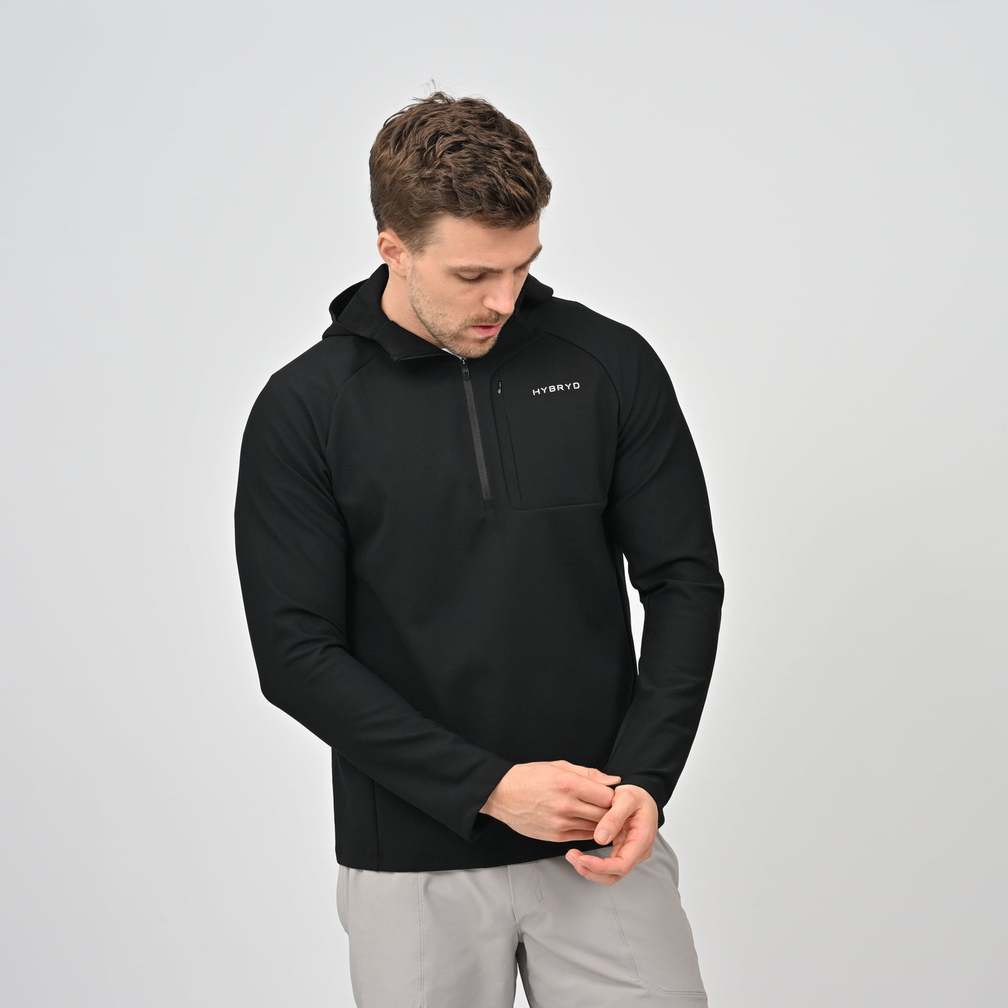 Man wearing a black pullover with a Hybryd logo on a light gray background