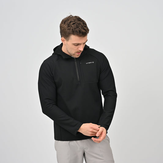 Man wearing a black pullover with a Hybryd logo on a light gray background