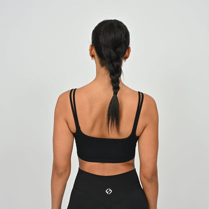 Person wearing a black Hybryd sports bra and leggings on a plain background