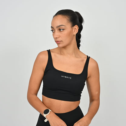 Woman wearing a black sports bra with 'HYBRYD' branding on a gray background