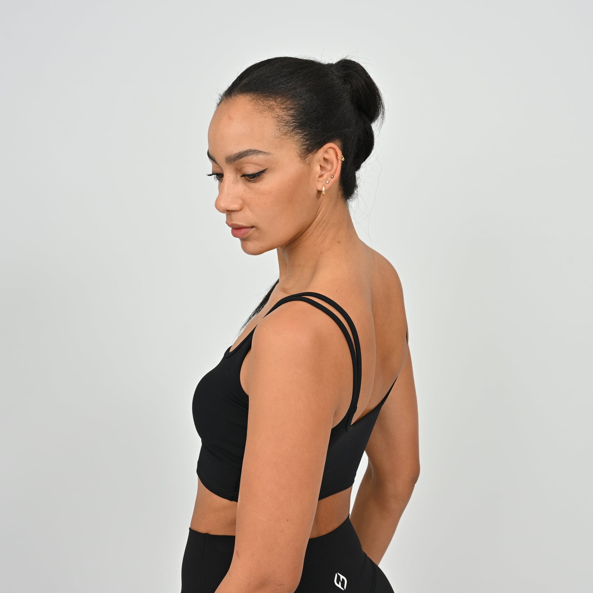 Woman wearing a Hybryd black sports bra top and leggings on a light gray background