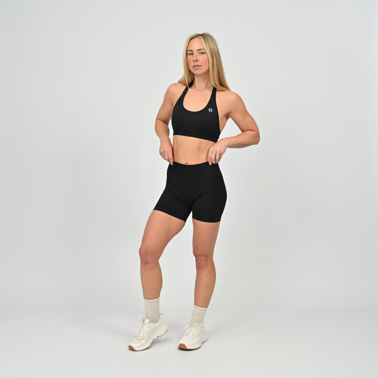 Woman wearing a black Hybryd sports bra and shorts set on a gray background