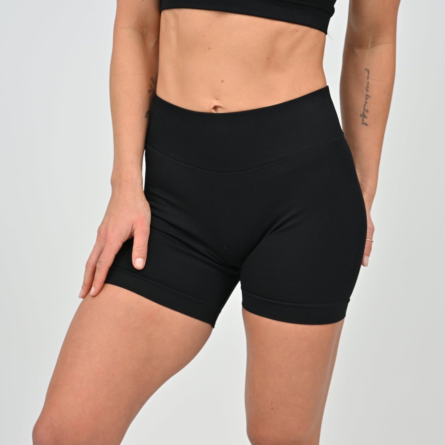 Person wearing black hybryd training shorts on a plain background