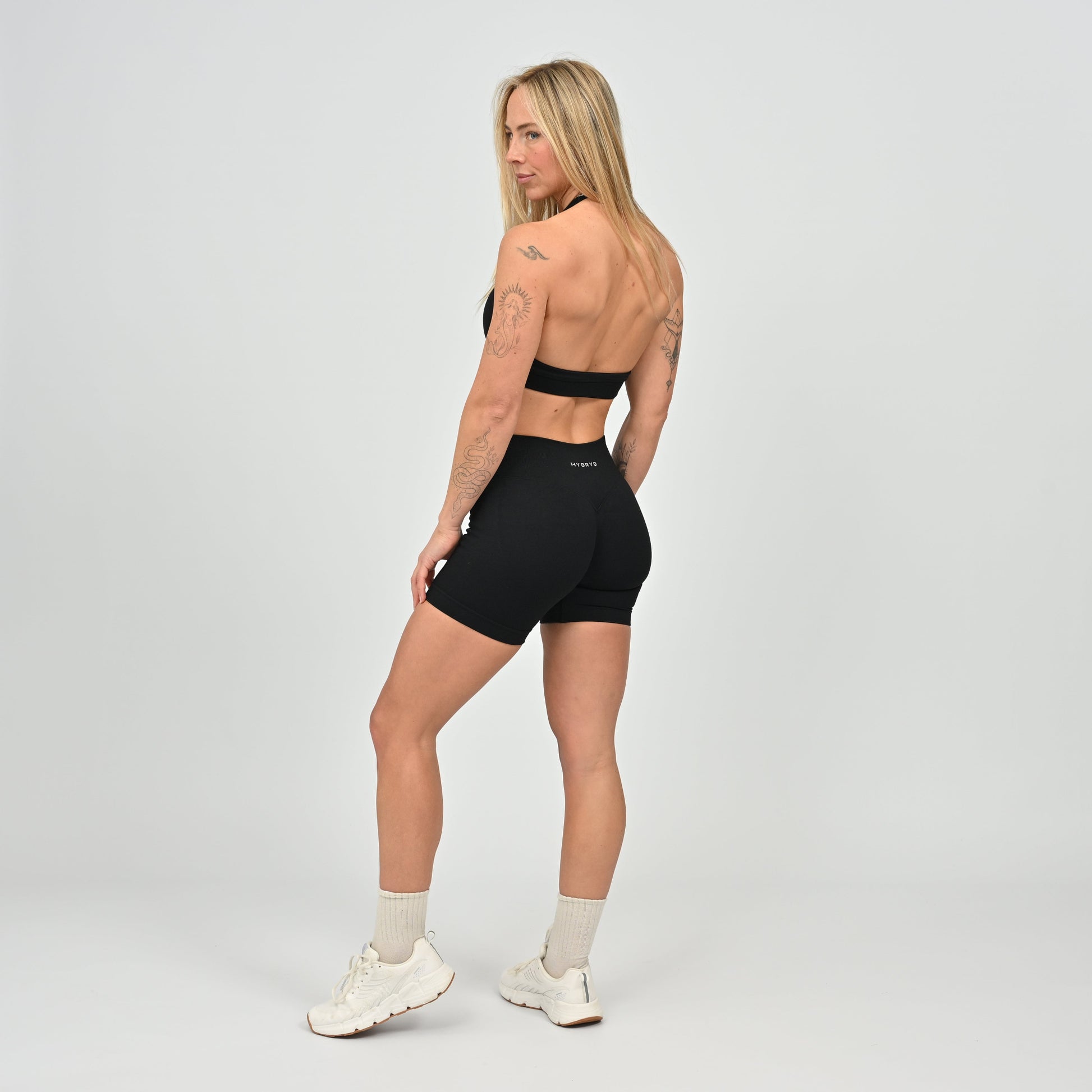 Woman wearing a black Hybryd sports bra and shorts set on a gray background