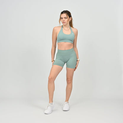 Woman wearing a green Hybryd halterneck sports bra and shorts set