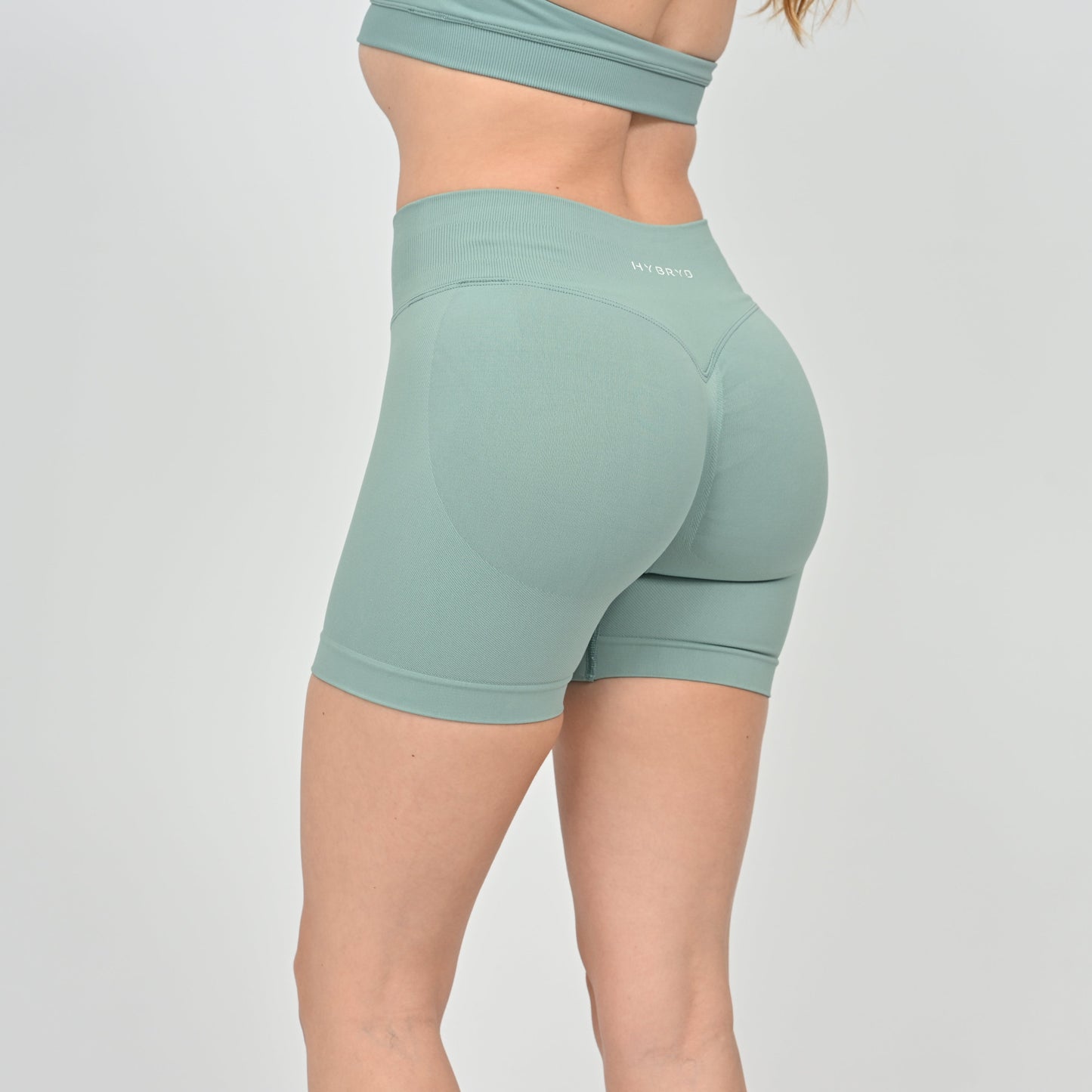 Hybryd green training shorts worn by a person on a light gray background.