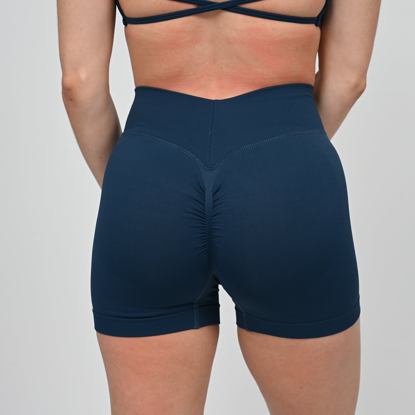 Navy blue athletic crossfit shorts with a bum scrunch worn by a Hybryd athlete on a light gray background