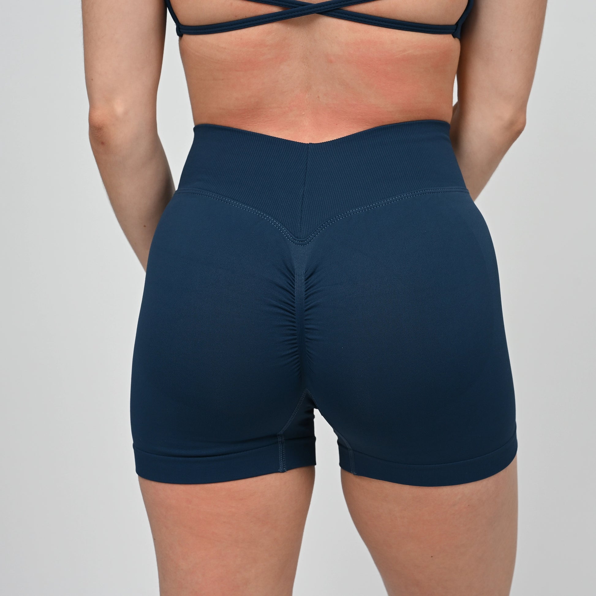 Navy blue athletic crossfit shorts with a bum scrunch worn by a Hybryd athlete on a light gray background