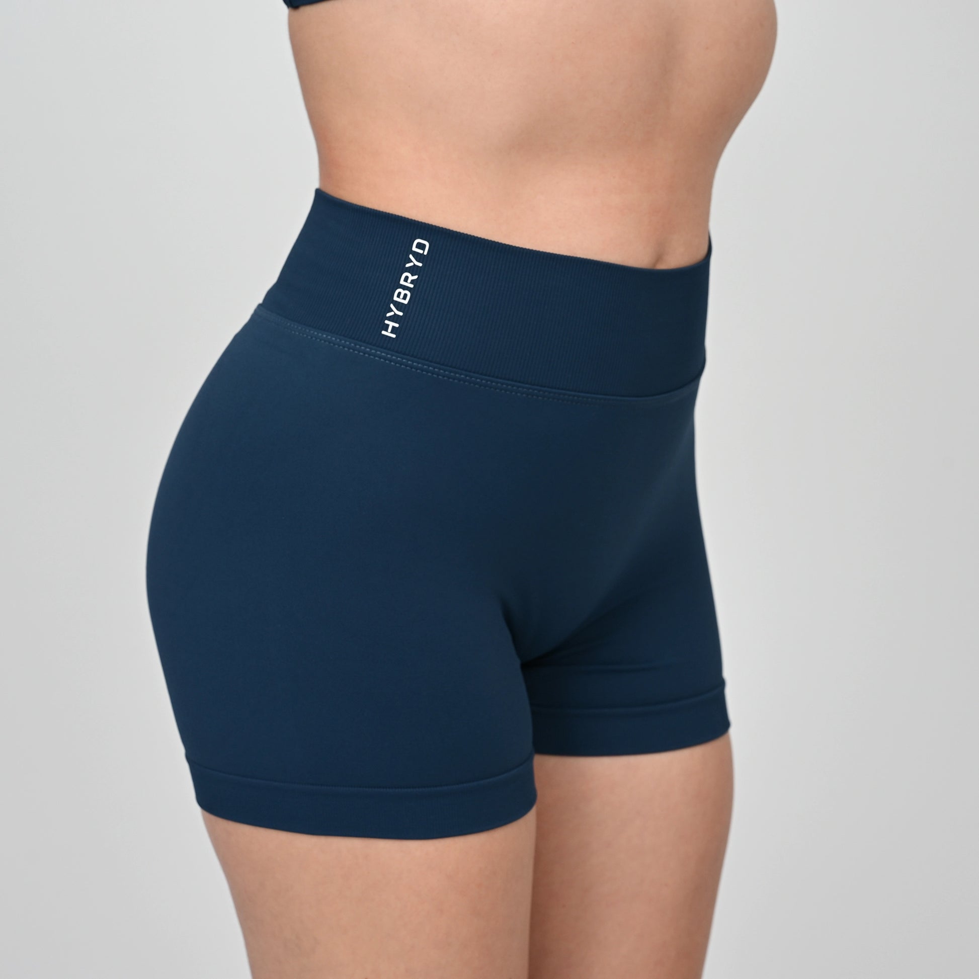 Navy blue athletic shorts with 'HYBRYD' logo and ribbed waistband on a gray background