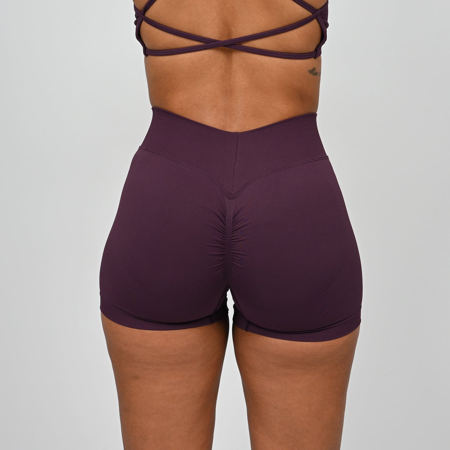 Purple gym workout shorts worn by a Hybryd athlete with a dipped waistband on a plain background
