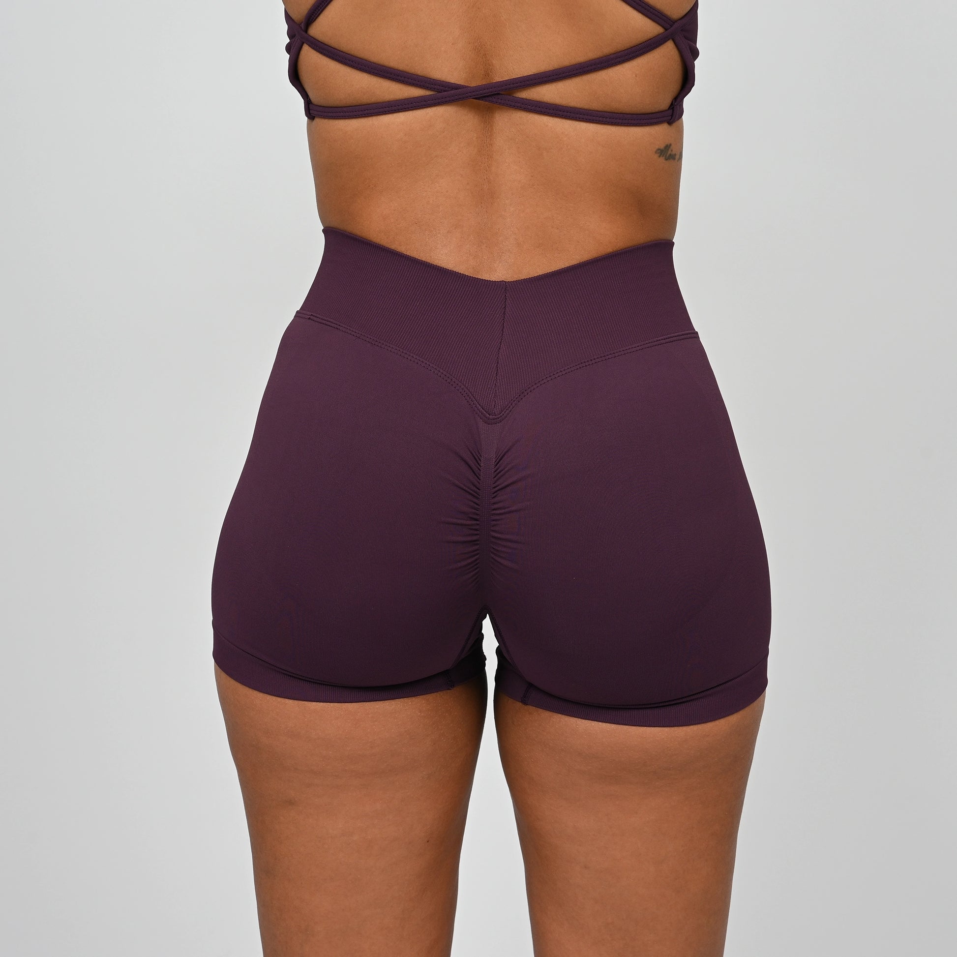 Purple gym workout shorts worn by a Hybryd athlete with a dipped waistband on a plain background
