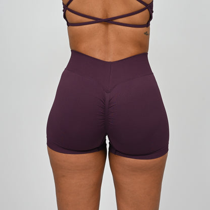 Purple gym workout shorts worn by a Hybryd athlete with a dipped waistband on a plain background