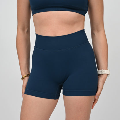 Hybryd athlete wearing navy blue workout gym shorts on a light gray background