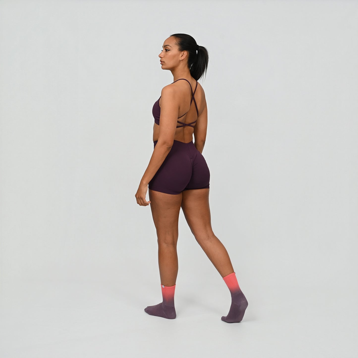 Crossfit athlete wearing a dark purple Hybryd gym outfit on a light gray background