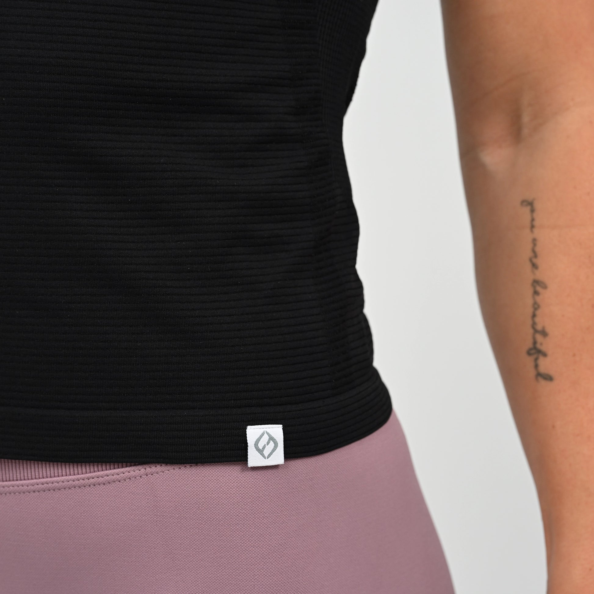 Black Hybryd tight ribbed gym top with a logo on a plain background