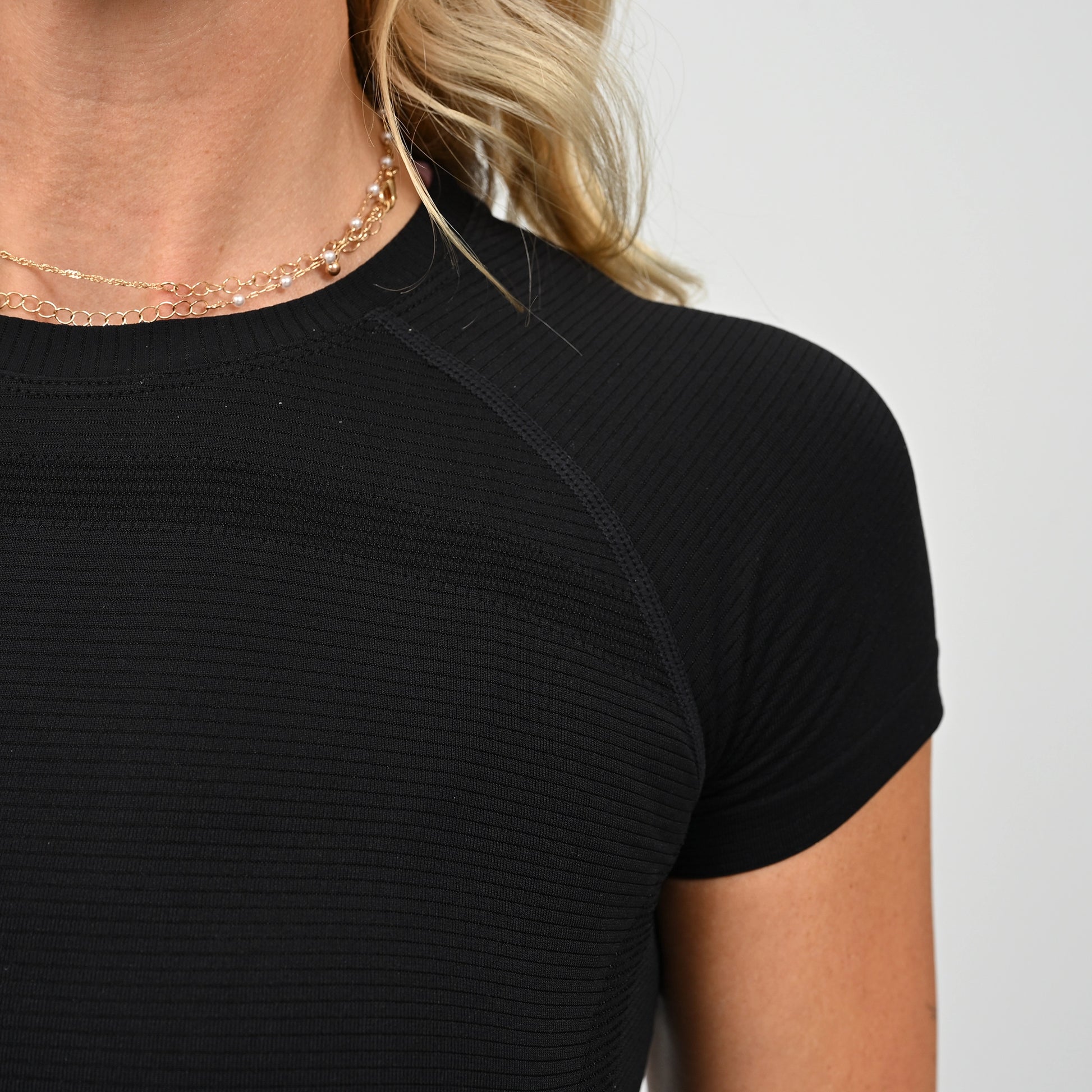 Close-up of an athlete wearing a black Hybryd ribbed top with a plain background