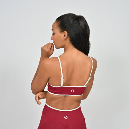 Gym Athlete wearing a crimson red Hybryd minimal sports bra and matching cinch bum leggings on a light gray background