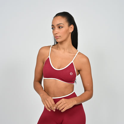 Gym Athlete wearing a crimson red Hybryd minimal sports bra and matching cinch bum leggings on a light gray background