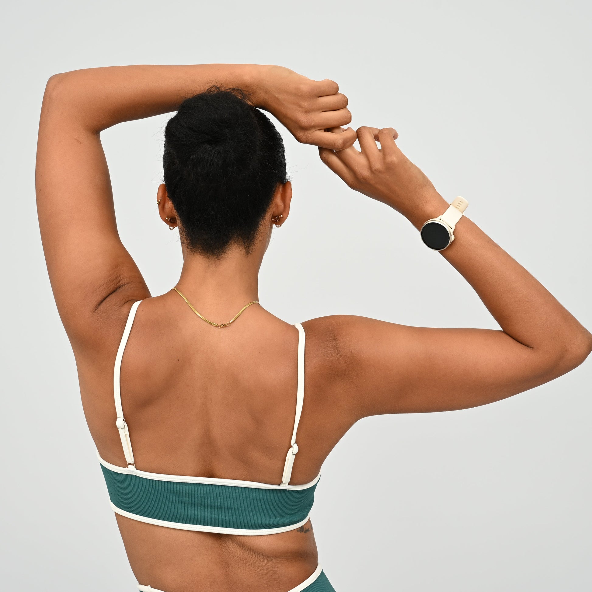 Gym Athlete wearing a jade Hybryd green minimal sports bra and matching cinch bum leggings  on a light gray background