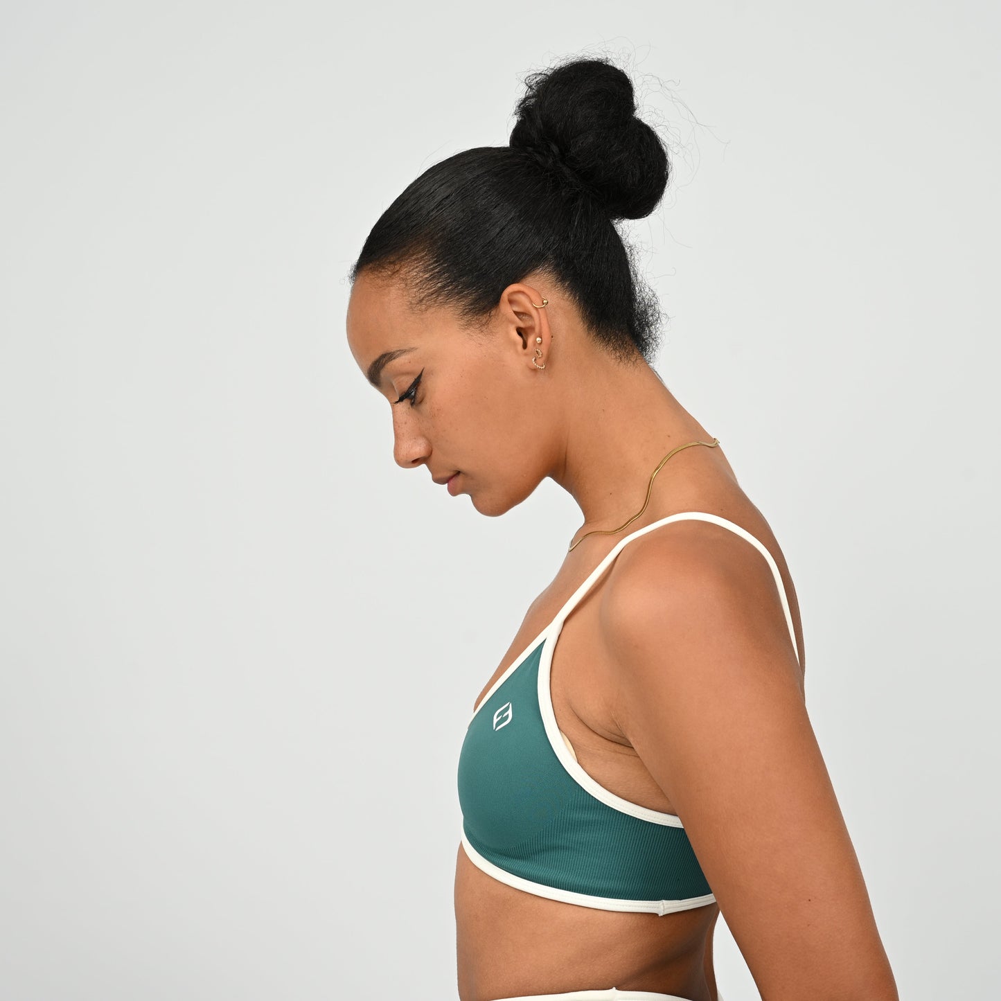 Gym Athlete wearing a jade Hybryd green minimal sports bra and matching cinch bum leggings  on a light gray background