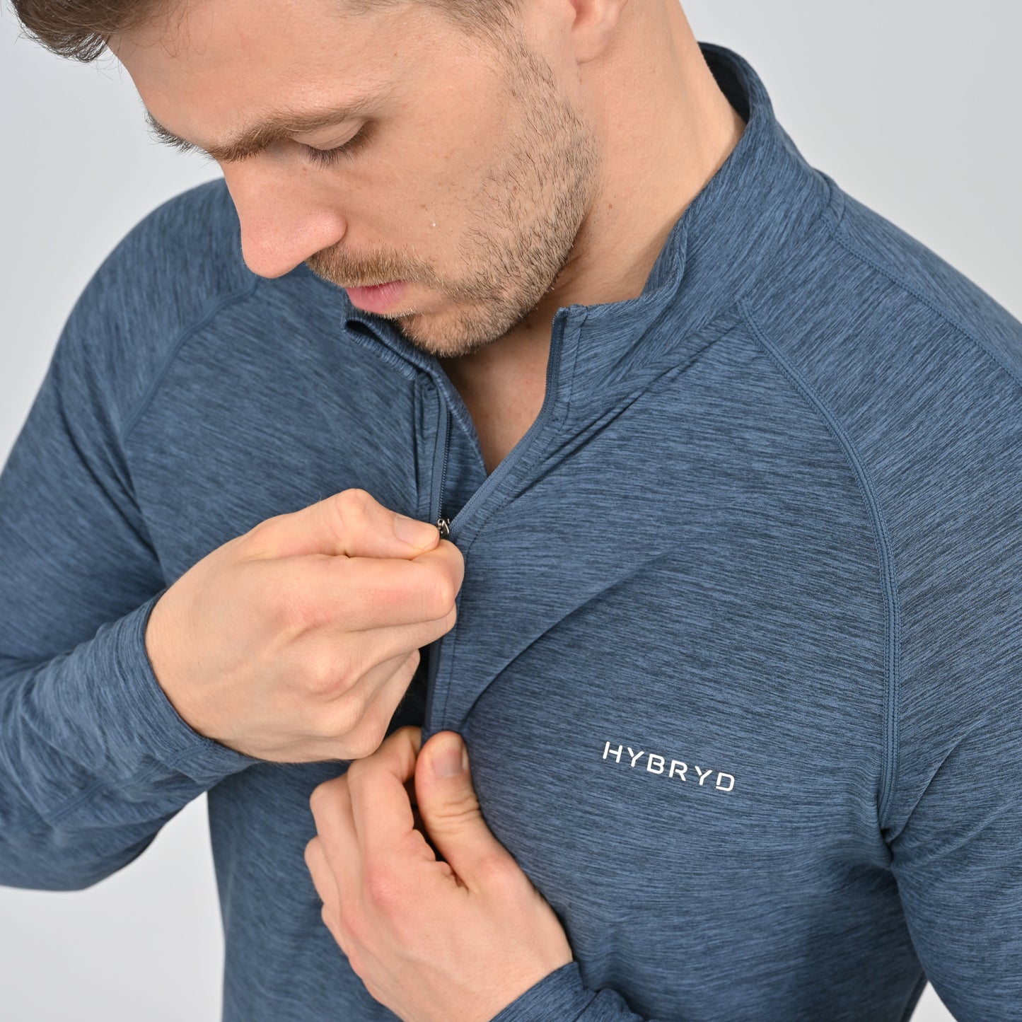 Man zipping a blue long sleeved tee with 'HYBRYD' logo