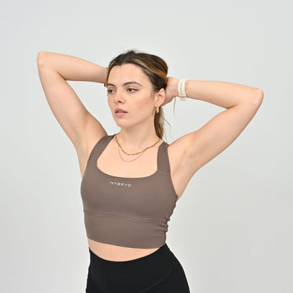Woman wearing a brown sports bra with 'HYBRYD' branding on a light gray background