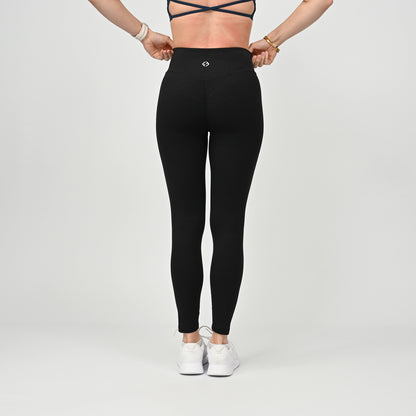 Person wearing black athletic active wear cinched bum leggings with a white logo on a light gray background