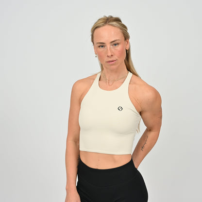 Woman wearing a stone colour sports bra and black leggings from Hybryd activewear