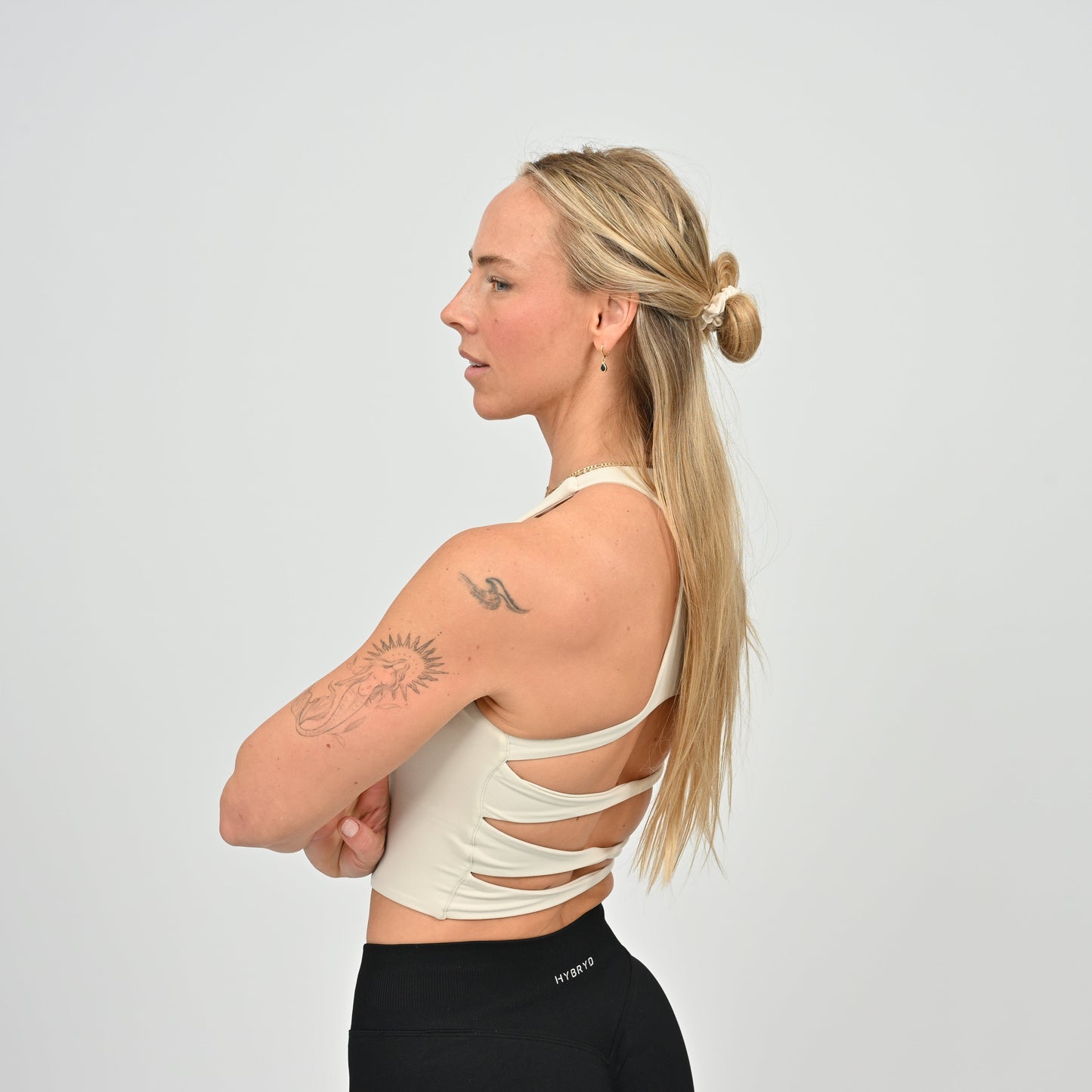 Woman wearing a stone colour sports bra with cut-out design from Hybryd gymwear