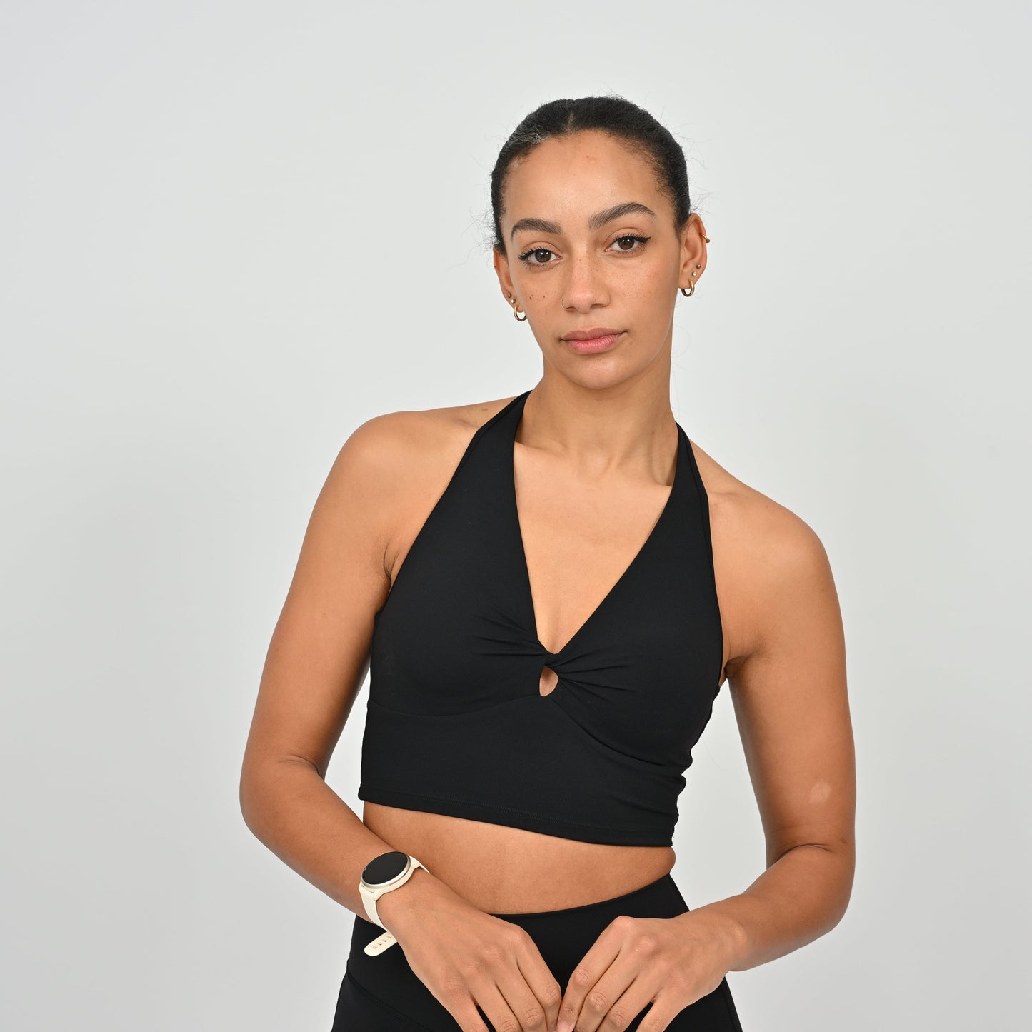 Woman wearing a black Hybryd halter bra against a plain background