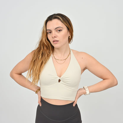 Woman wearing a Hybryd beige halter bra top and black pants on a plain background
