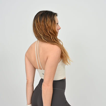 Woman wearing a Hybryd white halter sports bra and gray leggings on a plain background