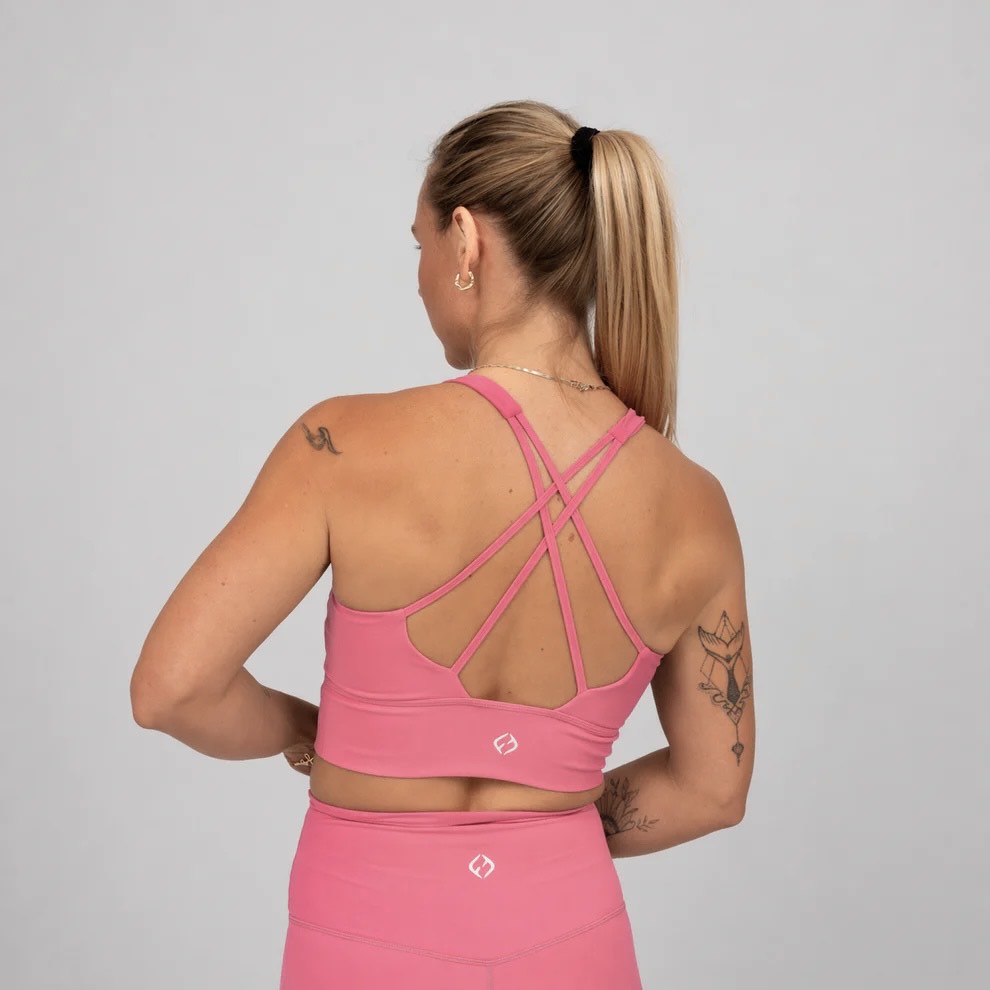 Woman wearing a pink hybryd sports bra and leggings with a gray background