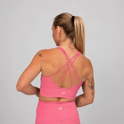 Woman wearing a pink hybryd sports bra and leggings with a gray background