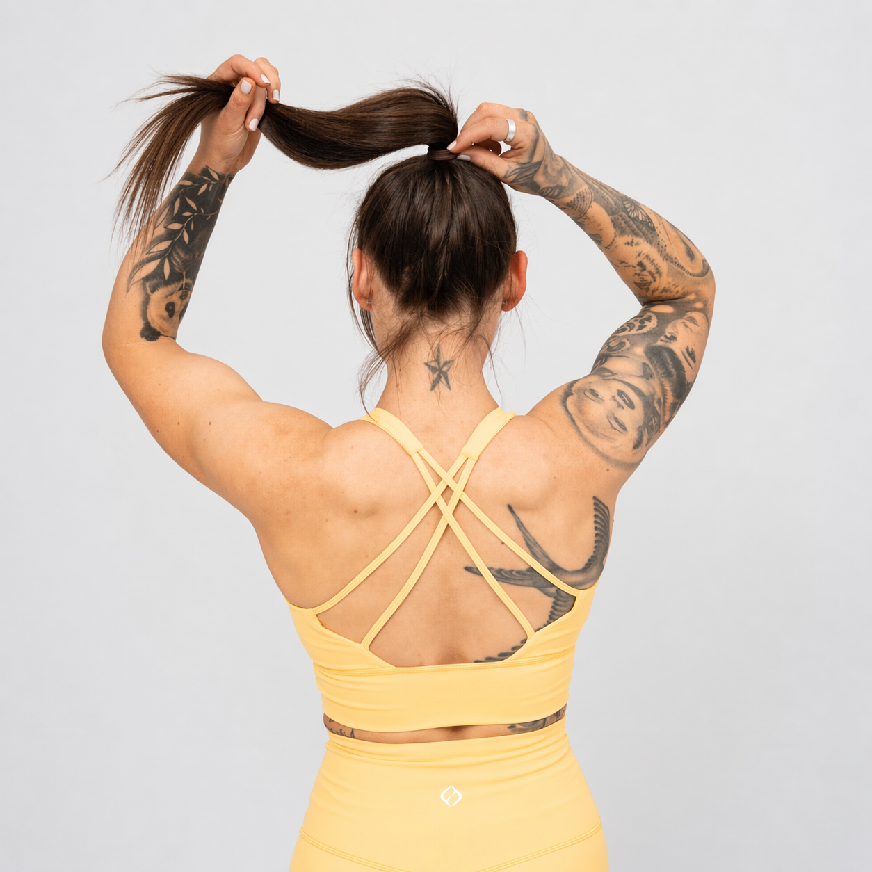 Person wearing a yellow sports bra with criss-cross straps from Hybryd activewear