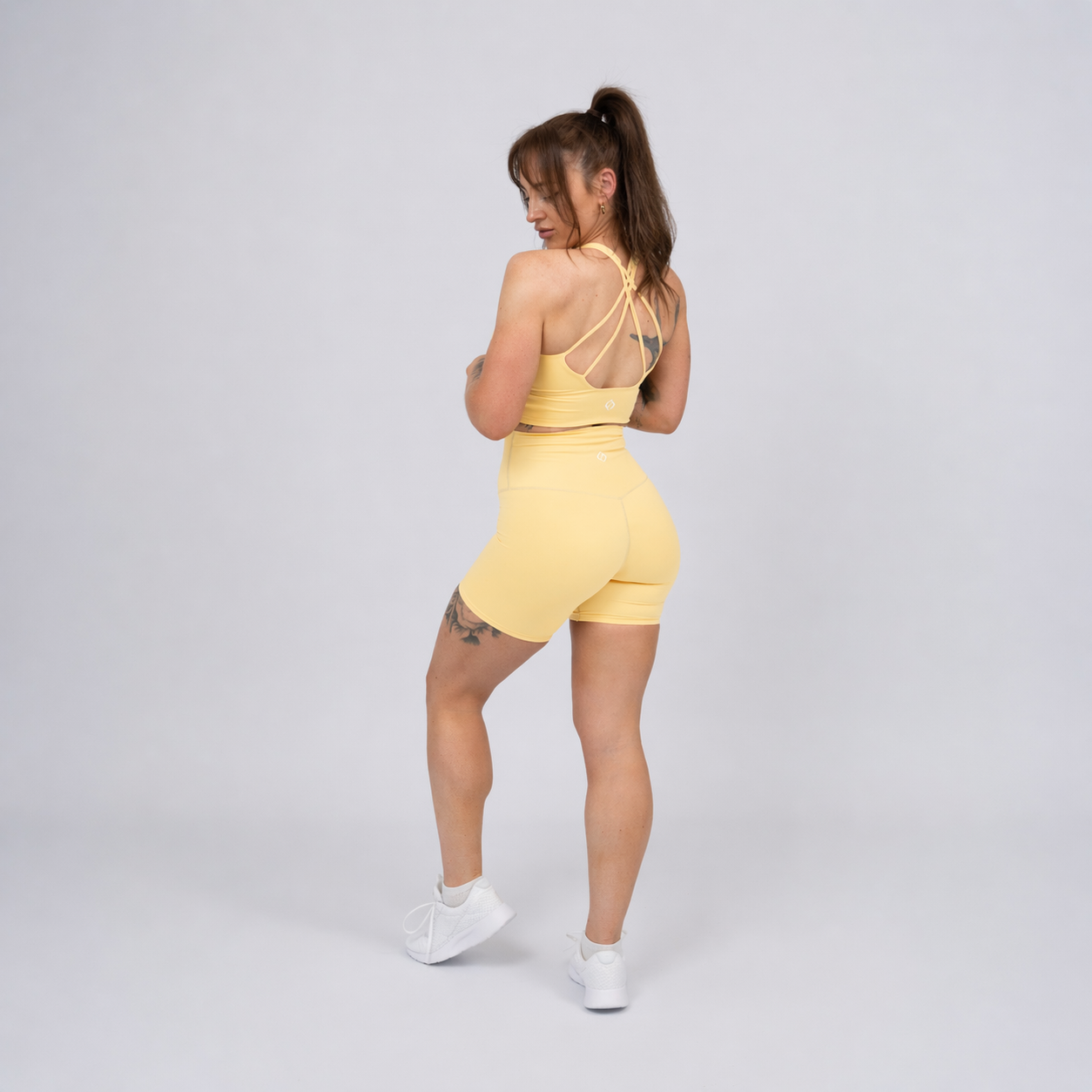 Woman wearing a yellow Hybryd matching set. Shorts and bra.